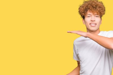 Büyük ve büyük boy işaret, ölçü birimi sembol gösteren elleriyle işaret casual beyaz t-shirt giyen afro saçlı Genç yakışıklı adam. Kameraya bakarak gülümsüyordu. Ölçüm kavramı.