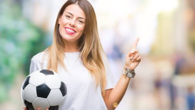 Futbol topu izole arka plan üzerinde çok mutlu el ve parmak ile tarafına işaret tutan genç güzel kadın