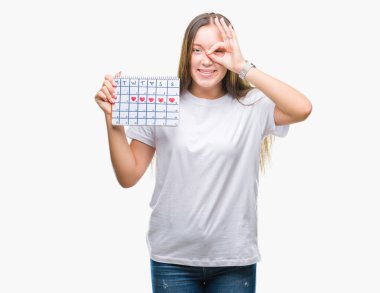 Adet takvim ile mutlu yüz el parmaklarının arasından seyir göz üzerinde ok işaretiyle yapıyor gülümseyen izole arka plan üzerinde tutan genç beyaz kadın