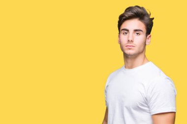 Yüzünde ciddi bir ifade ile izole arka plan üzerinde beyaz t-shirt giyen genç yakışıklı adam. Basit ve doğal kameraya bakıyor.