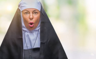 Orta yaş üst düzey Hıristiyan Katolik Rahibe kadın izole arka plan korkuyor ve sürpriz ifade ile şok korku ve yüz heyecanlı.