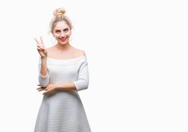 Genç güzel sarışın ve mavi gözlü kadın mutlu yüz zafer işareti yaparken kameraya göz kırpıyor ile gülümseyen izole arka plan yüzünden. İki numaralı.