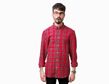 Korkuyor ve şok sürpriz ifade, korku ve heyecan yüz ile izole arka plan üzerinde gözlük takan genç yakışıklı adam.