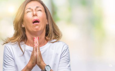 Orta yaş İspanyol kadın kıdemli yalvarıyor ve umut ifade yüzünde çok duygusal ve endişe ile birlikte elleriyle dua izole arka plan üzerinde. Bağışlanmak. Din kavramı.