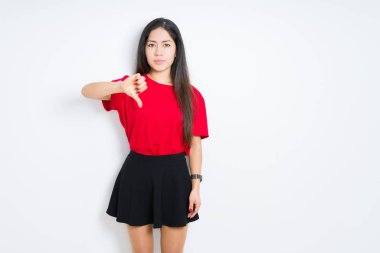 Mutsuz ve kızgın ret gösterilen ve başparmak aşağı hareketi ile negatif seyir arka plan üzerinde kırmızı t-shirt ve etek giyen güzel esmer kadın izole. Kötü ifade.