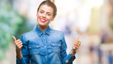 Genç güzel kadın el ile pozitif jest yapıyor izole arka plan başarı işareti yüzünden başparmak gülümseyen ve mutlu. Neşeli bir ifadeyle, kazanan jest kameraya bakıyor.