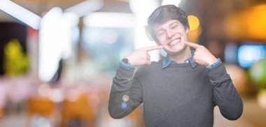 Genç yakışıklı zarif adam kendinden emin gösterilen ve işaret parmakları diş ve ağız ile gülümseyen izole arka plan üzerinde. Sağlık kavramı.