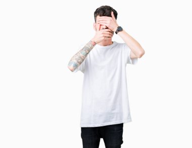 Yakışıklı delikanlı izole arka plan kaplaması gözler ve ağız el ile üzerine beyaz t-shirt giyen şaşırttı ve şok. Duygu gizleme