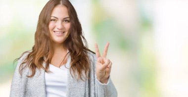 Artı boyutu genç kadın güzel kış ceket üzerinde arka plan mutlu yüz zafer işareti yaparken kameraya göz kırpıyor ile gülümseyen izole. İki numaralı.