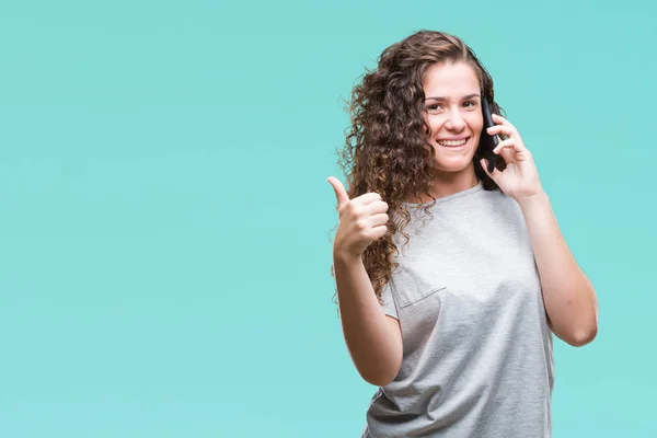 年轻的黑发女孩在智能手机上交谈在孤立的背景快乐与灿烂的微笑做确定的迹象 用手指竖起大拇指 优秀的标志 — 图库照片