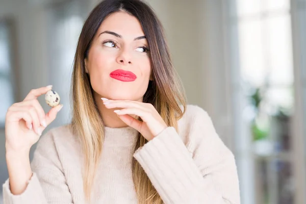 Young Beautiful Woman Holding Fresh Quail Egg Home Serious Face — Stock Photo, Image