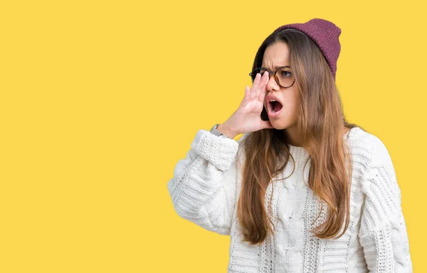 若い美しいブルネット流行に敏感な女性が叫び 口の中に手の側に大声で叫んで孤立の背景にメガネと冬の帽子を着てします 通信の概念 — ストック写真