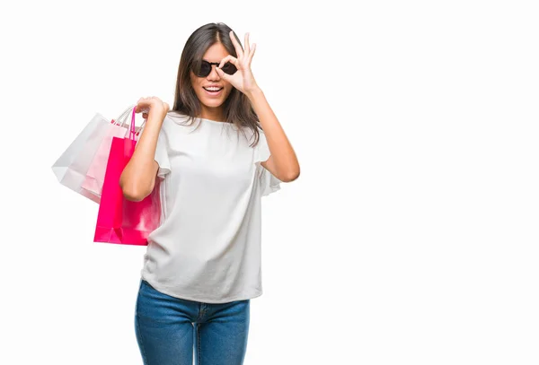 指を通して見る目に手で サインをして笑っている幸せそうな顔で孤立した背景の上販売のショッピング バッグを保持若いアジア女性 — ストック写真