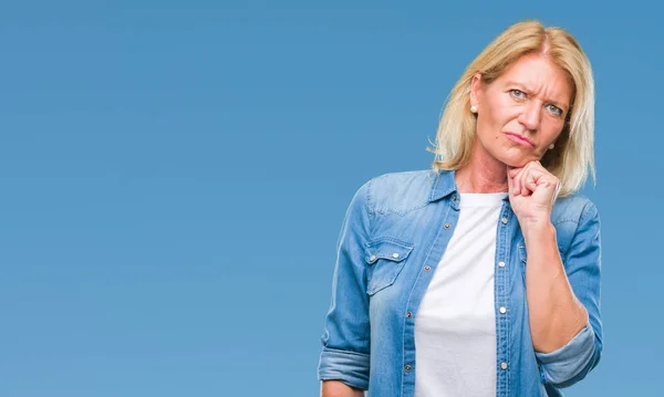 Middle age blonde woman over isolated background with hand on chin thinking about question, pensive expression. Smiling with thoughtful face. Doubt concept.