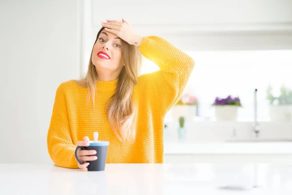 Young beautiful woman drinking a cup of coffee at home stressed with hand on head, shocked with shame and surprise face, angry and frustrated. Fear and upset for mistake.