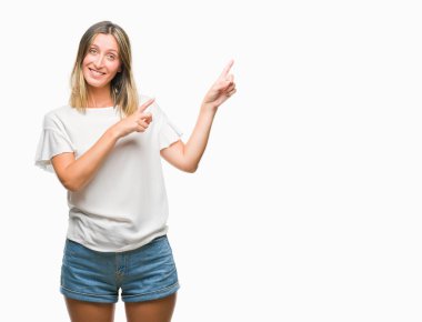 Gülümseyen ve iki elleri ve parmakları ile tarafına işaret kamera bakarak izole arka plan üzerinde genç güzel kadın.