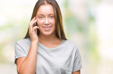 Genç güzel beyaz kadın smartphone üzerinde duran ve diş gösterilen kendine güvenen bir gülümsemeyle gülümseyerek mutlu bir yüz ile izole arka plan üzerinde söz