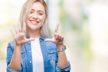 Genç Sarışın kadın gösterilen ve parmakları ile işaret izole arka plan yüzünden kendinden emin ve mutlu gülümseyerek süre yedi numara.