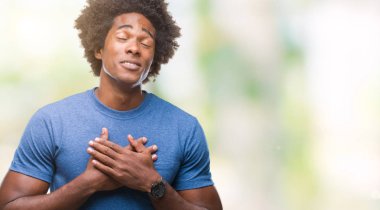 Afro Amerikalı adam ile gülümseyen izole arka plan üzerinde kapalı gözler ve yüzünde minnettar jest ile göğüs üzerinde eller. Sağlık kavramı.