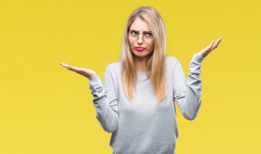 İzole arka plan clueless ve şaşkın bir ifadeyle kollar ve eller kaldırdı üzerinde gözlük takan genç güzel sarışın bir kadın. Şüphe kavramı.