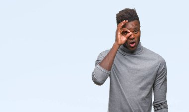 Sürpriz yüz, göz parmaklarının arasından seyir ile ok jest yapıyor izole arka plan üzerinde genç Afro-Amerikan adam şok. İmansız ifade.