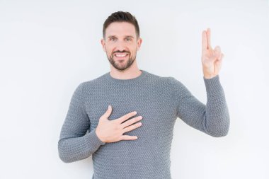 Casual kazak izole üzerinde giyen genç yakışıklı adam arka plan Swearing göğüs ve parmaklar, el ile bir sadakat sözü yemin yapma