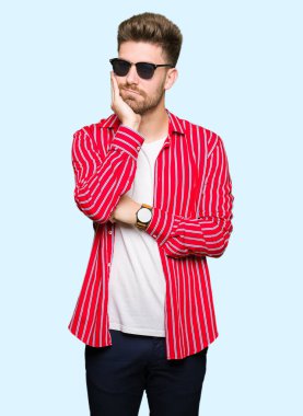 Yakışıklı delikanlı düşünme seyir yorgun ve sıkılmış depresyon sorunları ile güneş gözlüğü takıyor kollarını geçti.