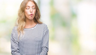 Üzerinde çizgili süveter giyen güzel genç sarışın kadın arka plan yapma balık yüz dudaklı, çılgın ve komik bir jest izole. Komik ifade.