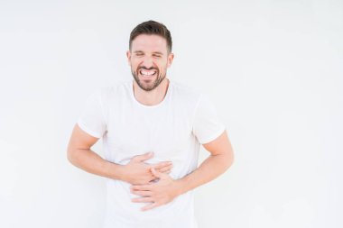 Casual beyaz t-shirt üzerinde izole giyen genç yakışıklı adam arka plan gülen ve komik deli şaka çünkü yüksek sesle zor gülüyor. Mutlu ifade.