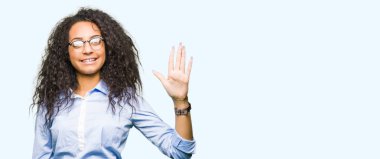 Kıvırcık saçlı gösterilen ve parmakları ile işaret gözlüklü genç güzel iş kız kendinden emin ve mutlu gülümseyerek süre beş numara.