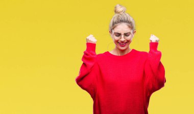 Kırmızı kazak ve gözlük izole arka kolları olan başarı için heyecan üzerinde giyen genç güzel sarışın kadın kutluyor zafer gülümseyen kaldırdı. Kazanan kavramı.