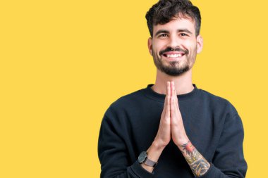 Yakışıklı delikanlı birlikte emin gülümseyen bağışlanmak ellerle dua izole arka plan üzerinde.