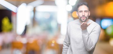 Bir öpücük el ile güzel ve seksi olmak hava üfleme kamera bakarak izole arka plan üzerinde sweatshirt giyen genç yakışıklı adam. Aşk ifade.