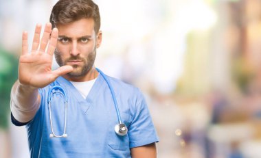 Genç yakışıklı elin avuç durağı şarkı yapıyor izole arka plan üzerinde cerrah adam doktor. Negatif ve ciddi bir jest yüz ifadesiyle uyarı.