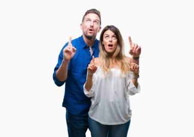 İzole arka plan üzerinde aşık genç çift hayret ve yukarıya bakıp parmakları ile işaret şaşırttı ve silah kaldırdı.