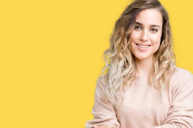 Sweatershirt üzerinde giyen genç güzel sarışın kadın mutlu yüz ile gülümseyerek kameraya seyir silah geçti arka plan izole. Olumlu bir kişi.