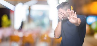 Yakışıklı delikanlı üzerinde kazak giyen izole elleriyle gözlerini kapsayan arka plan ve dur jest ile acı ve korku ifadesi. Utandım ve negatif kavramı.