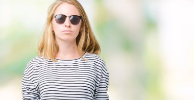 Güzel genç kadın yüzünde ciddi bir ifade ile izole arka plan üzerinde güneş gözlüğü takıyor. Basit ve doğal kameraya bakıyor.