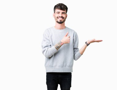 İzole arka plan gösteren palm el kazak giyen ve yukarıya, mutlu ve neşeli gülümseyen baş parmakları Tamam jest yapıyor yakışıklı delikanlı