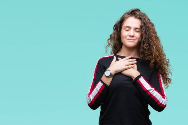 Casual göz kapalı gözler ile göğüs ellerinde ve yüzünde minnettar jest ile gülümseyen izole arka plan üzerinde giyen güzel genç esmer kıvırcık saçlı kız. Sağlık kavramı.