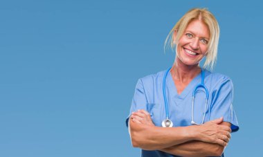 Orta yaş sarışın hemşire cerrah doktor kadın kameraya bakarak çapraz silah ile gülümseyen izole arka plan gülen surat. Olumlu bir kişi.