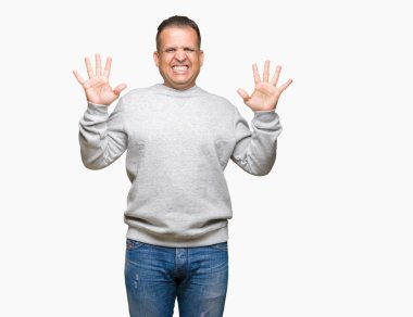 Gösterilen arka plan üzerinde spor kazak giyen orta yaş Arap adam izole ve parmakları ile işaret kendinden emin ve mutlu gülümseyerek süre on numara.