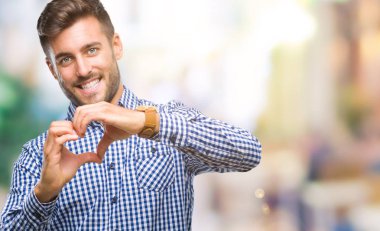 Yakışıklı delikanlı aşık kalp simgesi ve elleriyle şekil gösteren gülümseyen izole arka plan üzerinde. Romantik kavramı.