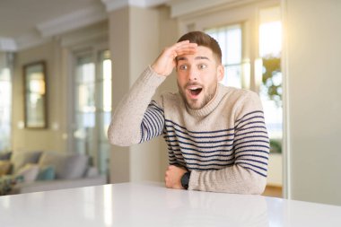 Genç yakışıklı adam evde çok mutlu ve gülümseyen uzakta el ile üzerine kafa arıyorum. Arama kavramı.