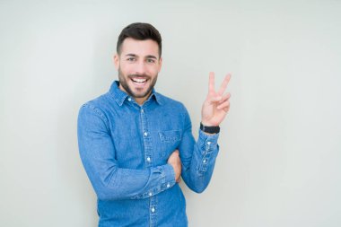 Mutlu yüz zafer işareti yaparken kameraya göz kırpıyor ile gülümseyen izole arka plan üzerinde genç yakışıklı adam. İki numaralı.