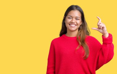 İzole arka plan gülümseyen ve süre seyir ve kamera boyutu işaret parmaklarıyla yapıyor el ile kendinden emin eller üzerinde kırmızı kış kazak giyen genç güzel esmer kadın. Ölçü kavramı.