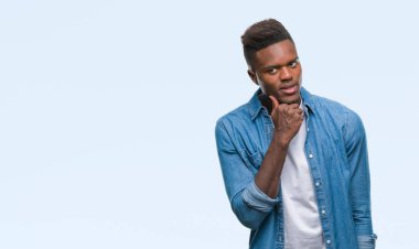 Afrikalı-Amerikalı genç çene düşünme hakkında soru, dalgın ifade üzerine el ile izole arka plan üzerinde. Düşünceli yüzüyle gülümsüyor. Şüphe kavramı.