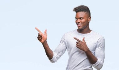 Gülümseyen ve iki elleri ve parmakları ile tarafına işaret kamera bakarak izole arka plan üzerinde genç Afro-Amerikan adam.