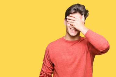 Yakışıklı genç gülümseyen ve gözler için sürpriz kapsayan yüz el ile gülüyor izole arka plan üzerinde. Kör kavramı.