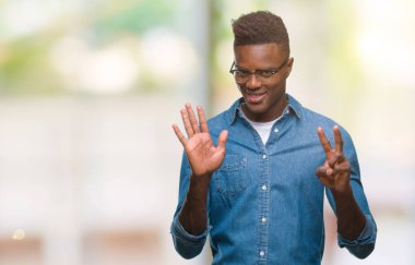 Gösterilen ve parmakları ile işaret izole arka plan üzerinde genç Afro-Amerikan adam kendinden emin ve mutlu gülümseyerek süre yedi numara.